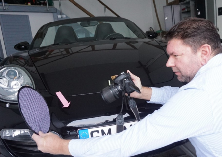 Michael Mußweiler, Kfz-Sachverständiger in Wiesbaden, präzise bei der Begutachtung eines schwarzen Cabriolets.